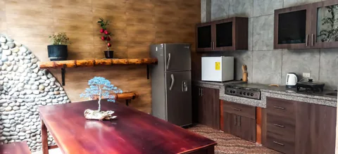 Shared kitchen with a wooden table, refrigerator and countertop.