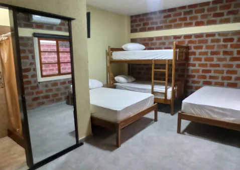 Guest room with wooden beds, a bunk bed and exposed-brick walls.