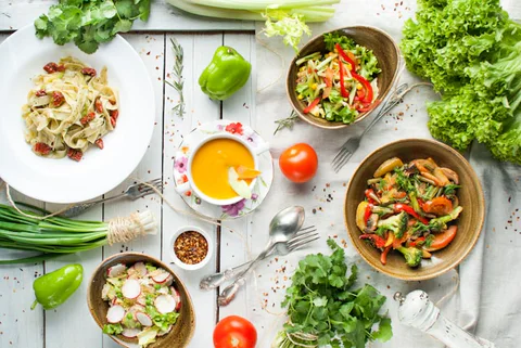 Plant-based dishes, salads and fresh vegetables arranged on a table.